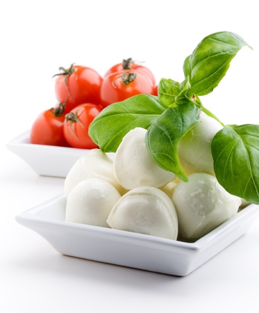 Mozzarella, tomatoes and fresh basil leaves on white backgroundの写真素材