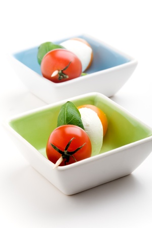 Mozzarella, tomatoes and fresh basil leaves on white backgroundの写真素材
