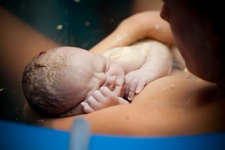 Newborn baby on his mothers arms right after deliveryの写真素材