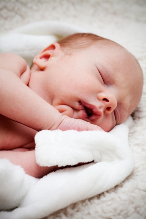 Newborn baby boy sleeping on white blanketの写真素材