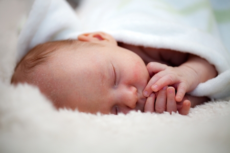 Newborn baby boy sleeping on white blanketの写真素材