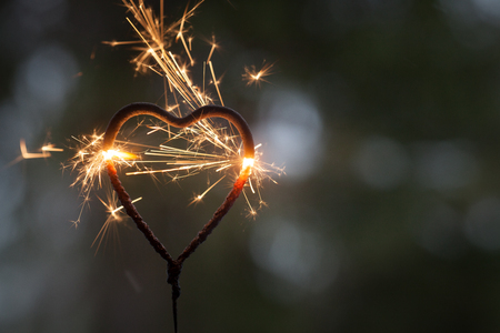 Heart shape sparkler burning in the darkの写真素材