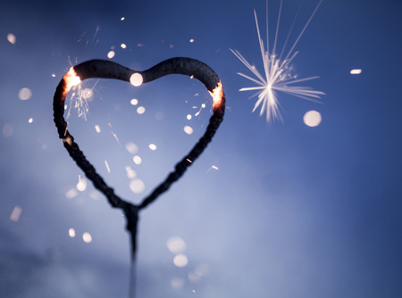 Heart shape sparkler burning and glowing in the darkの写真素材