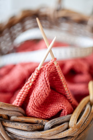 Close up photo of a knitting project in a basket with soft yarn wooden needles and a measuring tape...