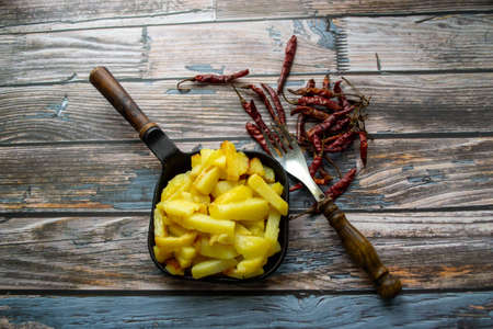 there is a frying pan with fried potatoes on a wooden backgroundの写真素材