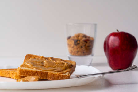 Sandwich with peanut butter, granola and apple for breakfast. Peanut butter toast on a white background.の写真素材