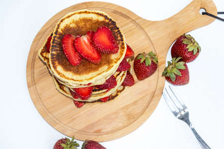 Pancakes with fresh strawberries isolated on white background. A stack of pancakes with...