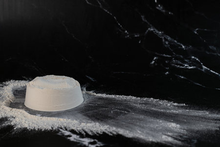 White flour in a bowl on a black background. Space for text.の写真素材