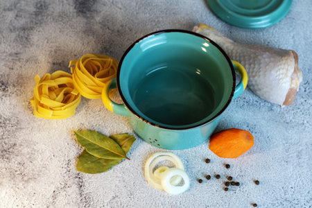 Ceramic pot with pasta and ingredients for cooking on a light background