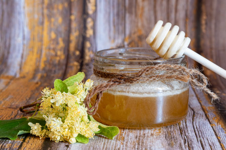 Jar of honey with linden flowers on a wooden background.の写真素材