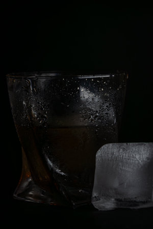 A glass of whiskey with ice cubes on a black background. Close-up.の写真素材