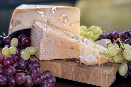 Cheese collection, variety of hard cheese parmesan roquefort with red and white grapes close up