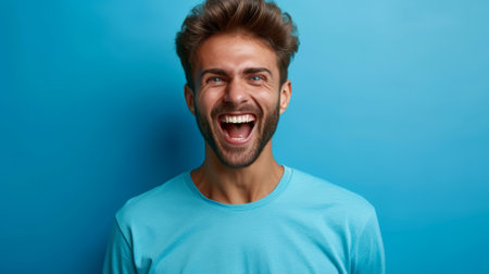 Bearded man in blue shirt laughs with mouth wide openの素材