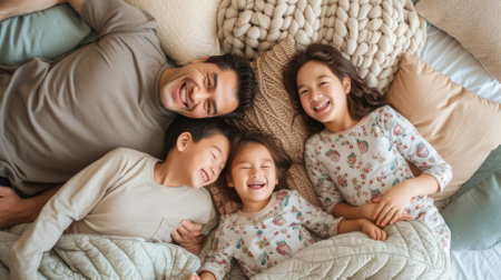 Happy family of four lying in bed togetherの素材