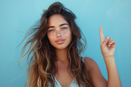 Portrait of a beautiful young woman with long brown hair and freckles, holding her finger upの素材