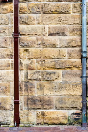Sandstone block wall with red drain pipeの写真素材