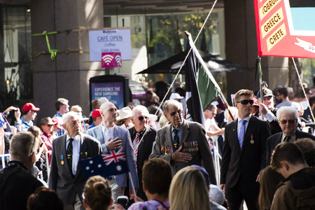 Group of veterans with their eyes left and their right hand over their heart paying respect to the War Memorial as they march down Elizabeth Stのeditorial素材