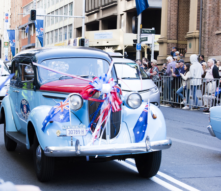 Old classic RSL cab with flags drives past the crowd down Elizabeth Stのeditorial素材