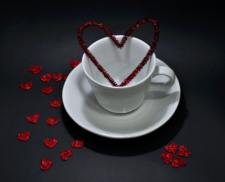 Coffee cup decorated with hearts for Valentine's Day on black backgroundの写真素材