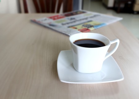 Coffee cup and newspaper on the wooden table.の写真素材