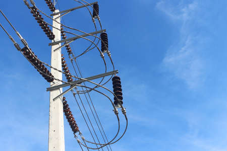 High voltage electrical insulator hanging on electric pole with blue sky background.