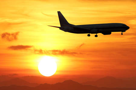 silhouette of Airplane on the air with sunset over the mountains with a beautiful golden sky.の写真素材