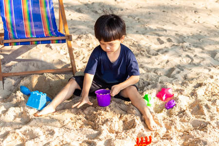Cute Asian boy playing with beach toys on the beach.の写真素材