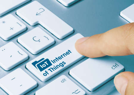 IoT Internet of Things Written on Blue Key of Metallic Keyboard. Finger pressing key.の写真素材