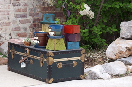 Flower pots and other items displayed on an old trunk outside a shopの写真素材