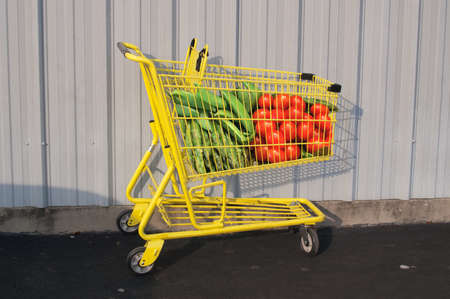 Giant fresh vegetables in a yellow grocery cartの写真素材