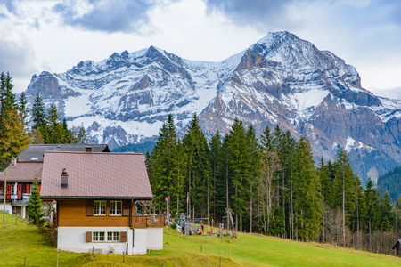 Traditional Swiss style houses on the green hills with forest in the Alps area of Switzerland, Europeのeditorial素材