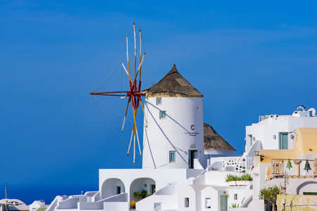 Windmill and traditional white buildings facing Aegean Sea in Oia, Santorini, Greece