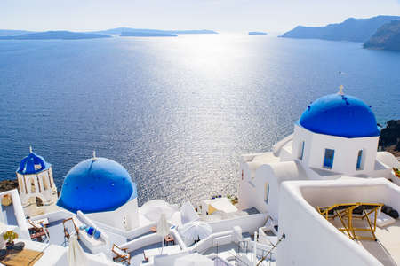 Blue domed church and traditional white houses facing Aegean Sea in Oia, Santorini, Greeceの写真素材