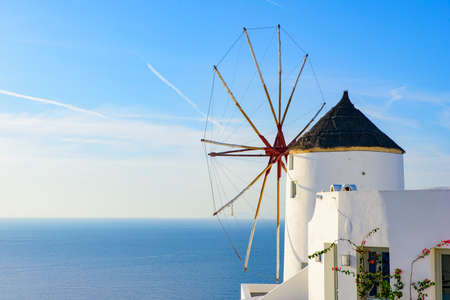 Windmill and traditional white buildings facing Aegean Sea in Oia, Santorini, Greeceの写真素材