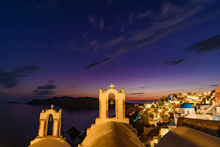 Night view of blue domed churches and bell tower facing Aegean Sea in Oia, Santorini, Greeceの写真素材