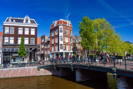 People riding bikes along the canal in Amsterdam, Netherlands
