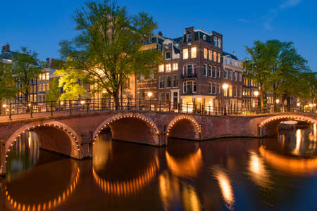 Reflection of bridge along the canal at night in Amsterdam, Netherlandsの写真素材