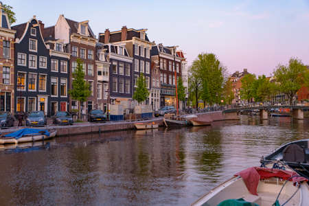 Buildings and boats along the canal at sunset time in Amsterdam, Netherlandsのeditorial素材