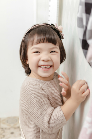 Little pretty Asian girl standing in a normal indoor life background.の写真素材