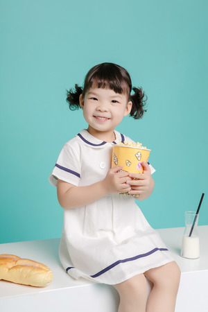 Little pretty Asian girl laughing portrait with milk and bread, healthy and happy lifestyle.の写真素材