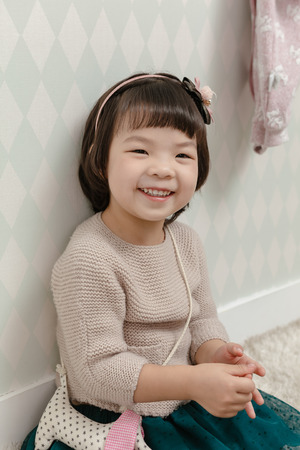 Little pretty Asian girl standing in a normal indoor life background.の写真素材