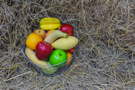 Apple,Banana,Orange,Persimmon and peach in iron basket with hayの写真素材