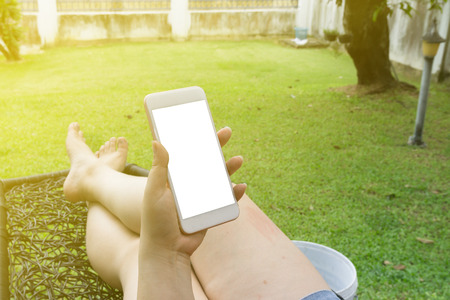 Woman lying and hold smartphone with white screen backgroundの写真素材