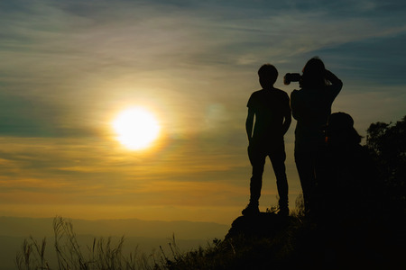 Unidentifind Man and Women take photo with sunset on high mountain background Silhouette Styleの写真素材