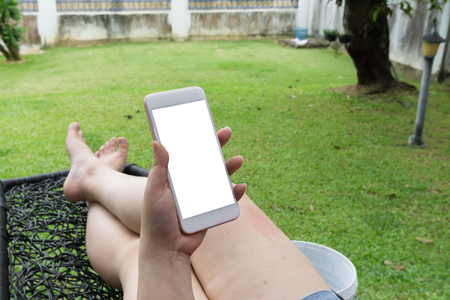 Woman lying and hold smartphone with white screen backgroundの写真素材
