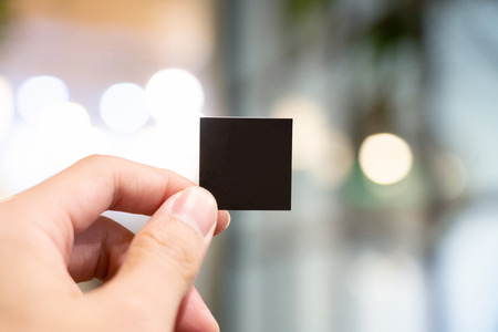 Hand holding blank black small paper with blury background.の写真素材