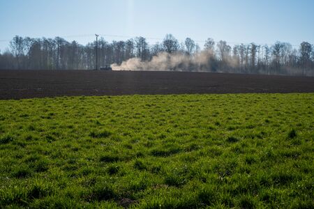 Farmer plowing the field. Cultivating tractor in the field. Red farm tractor with a plow in a farm field. Tractor and Plowの写真素材
