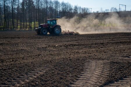 Farmer in tractor preparing land with seedbed cultivator, morning sunの写真素材