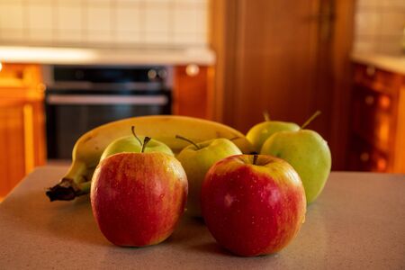 apples and bananas on the kitchen counter in the background oven and doorの写真素材