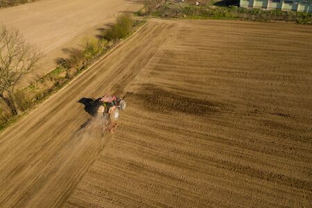 aerial shot of Farmer in tractor preparing land with seedbed cultivator, morning sunの写真素材